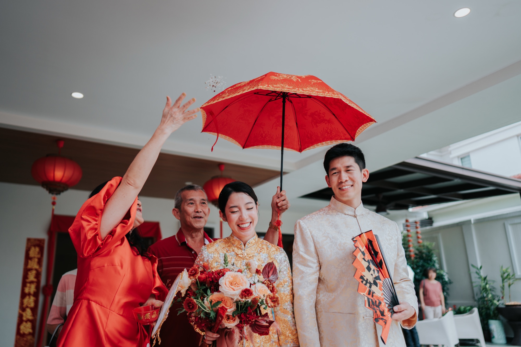 Bride and groom walking under a red parasol at a Chinese wedding in Kuala Lumpur