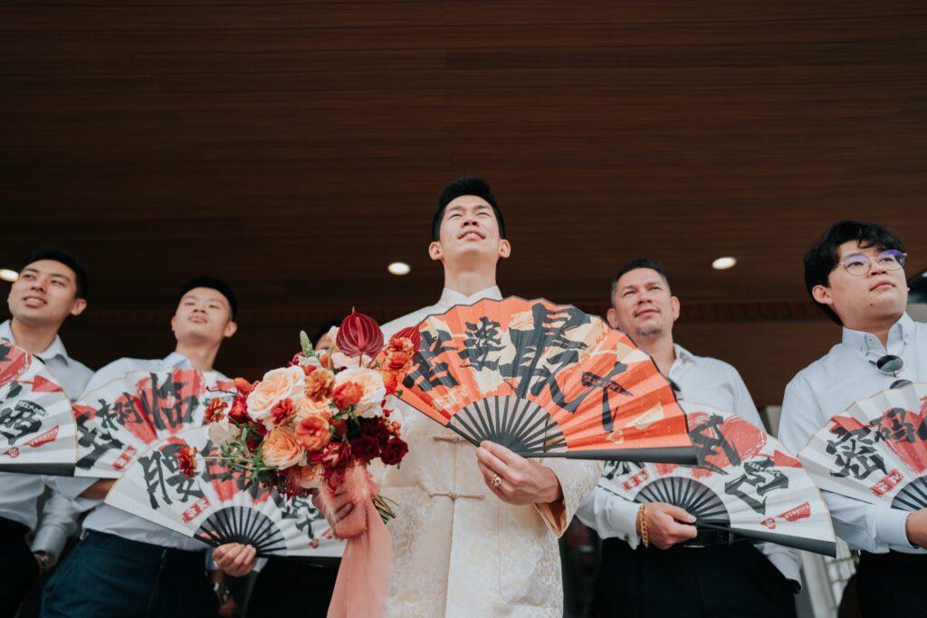 Groomsmen with fans during the door games at a Chinese wedding in Kuala Lumpur
