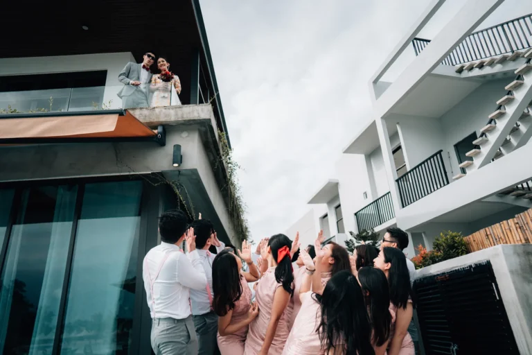 A couple on a balcony as guests wave from below
