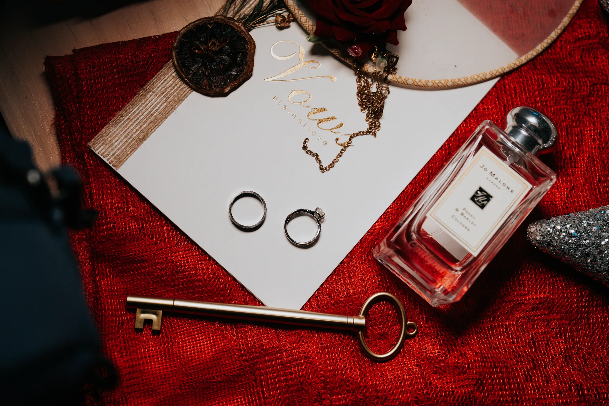 Rings, a key and perfume on red cloth