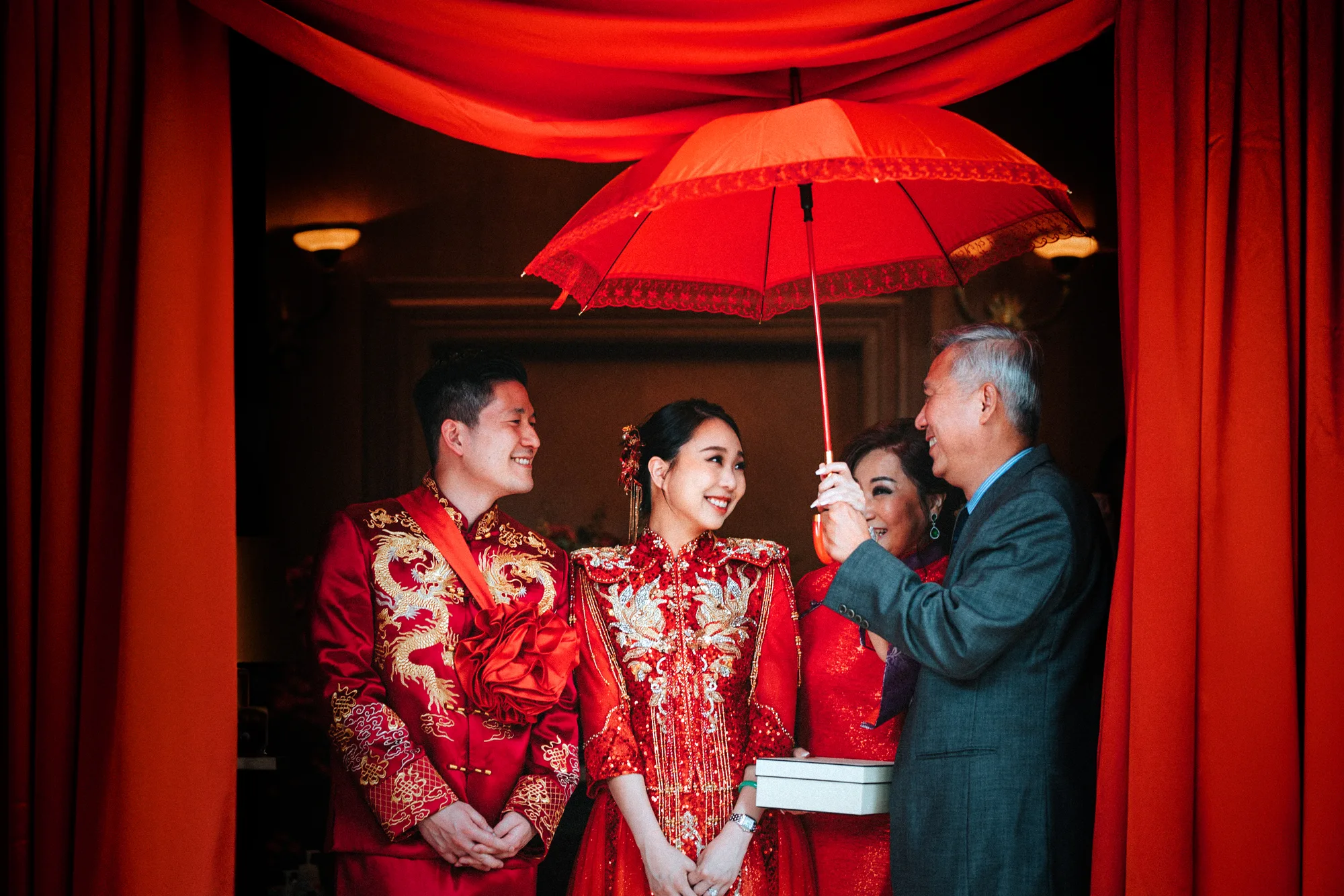 Cherise and John with their family under the red parasol at a Chinese wedding in Kuala Lumpur
