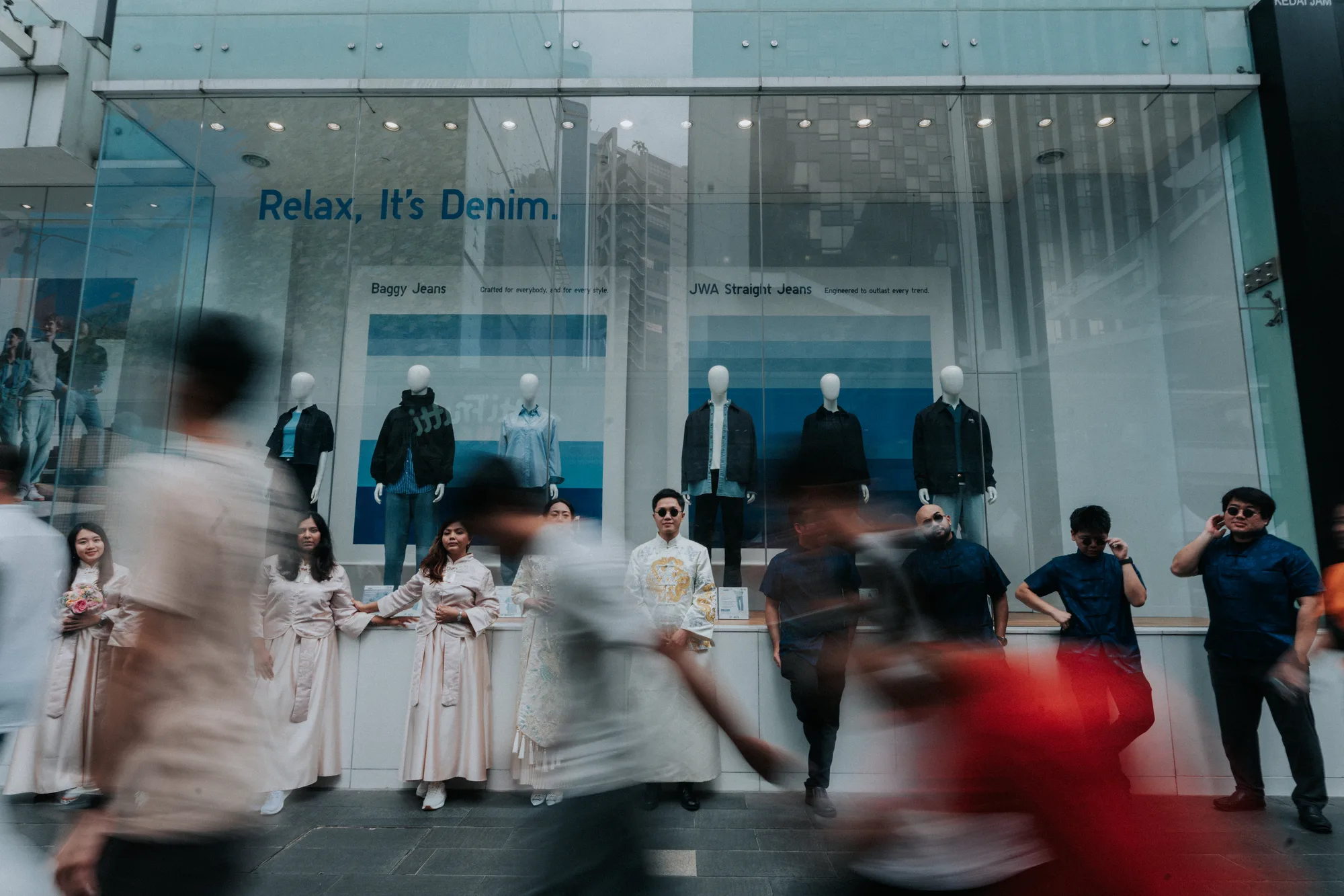 The wedding party standing still at a shop window while people walk past in a blur