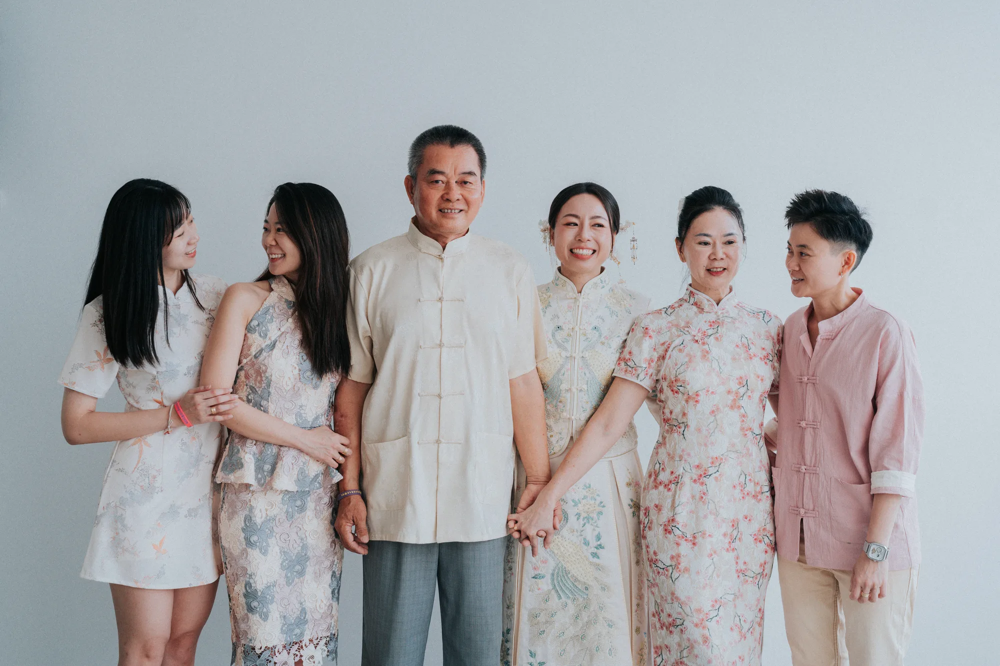 A family of six poses together in traditional attire against a plain white backdrop