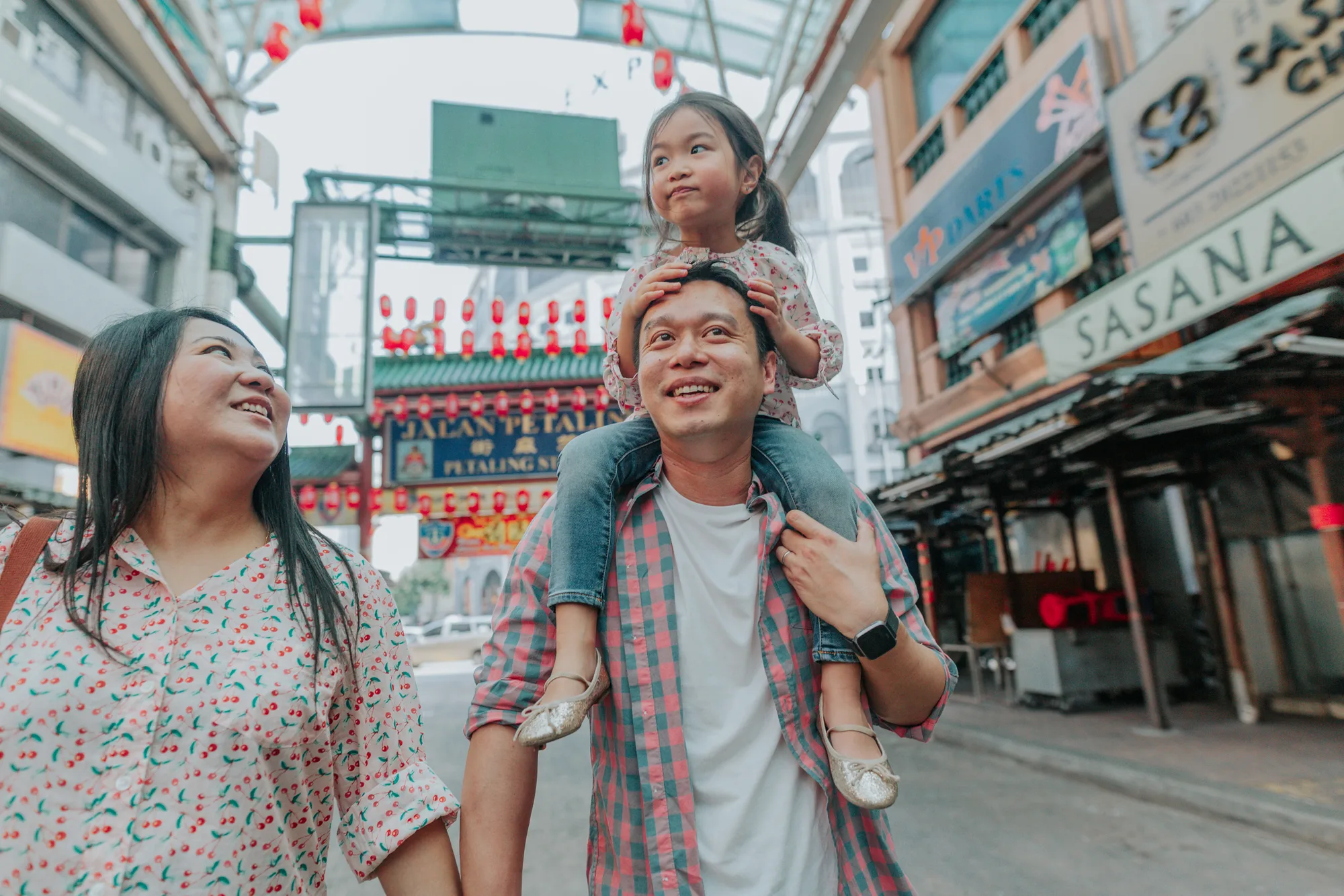 A family of three plays in a street hung with red lanterns