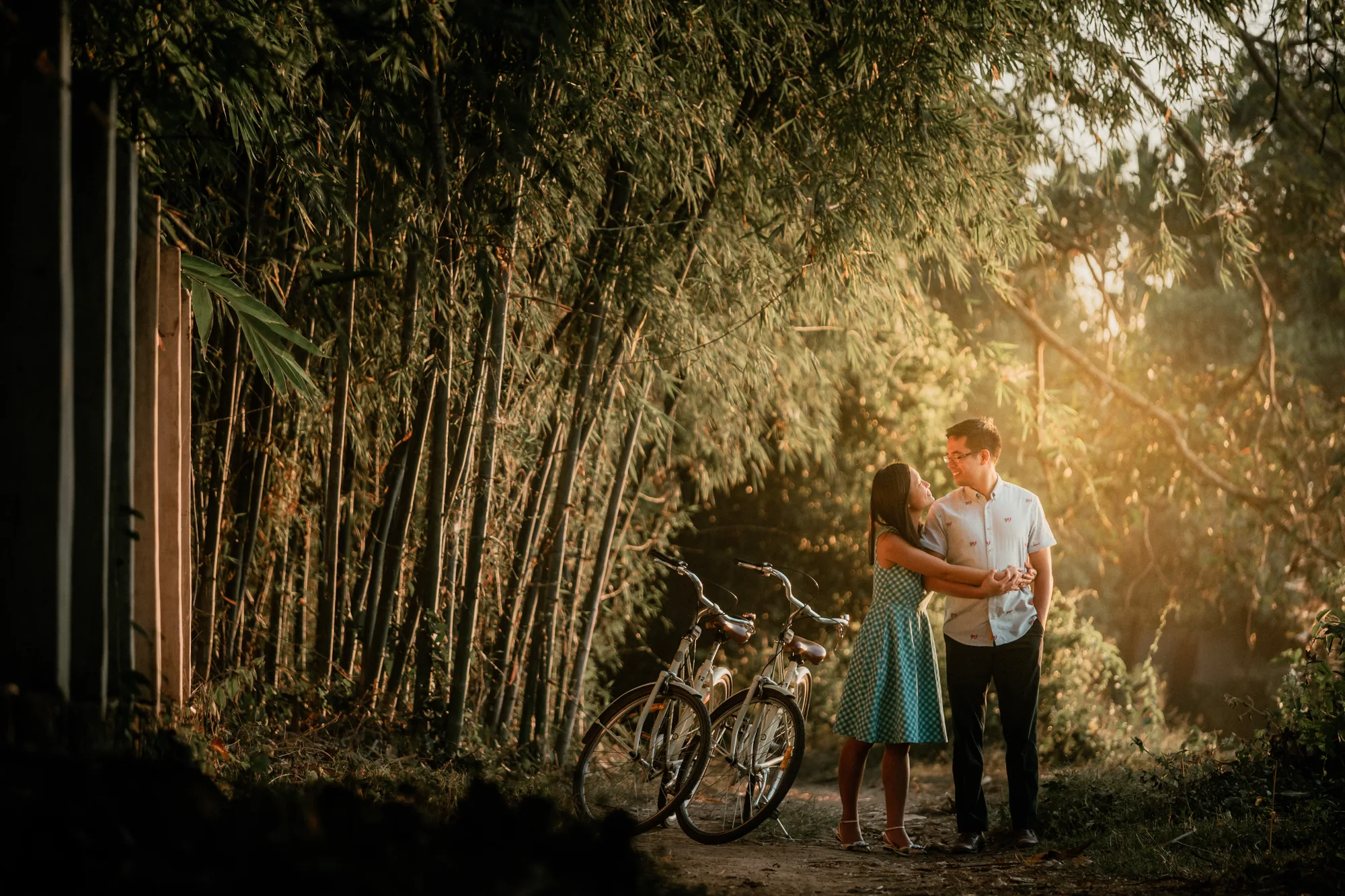 A couple embraces in a serene bamboo grove bathed in golden sunlight.
