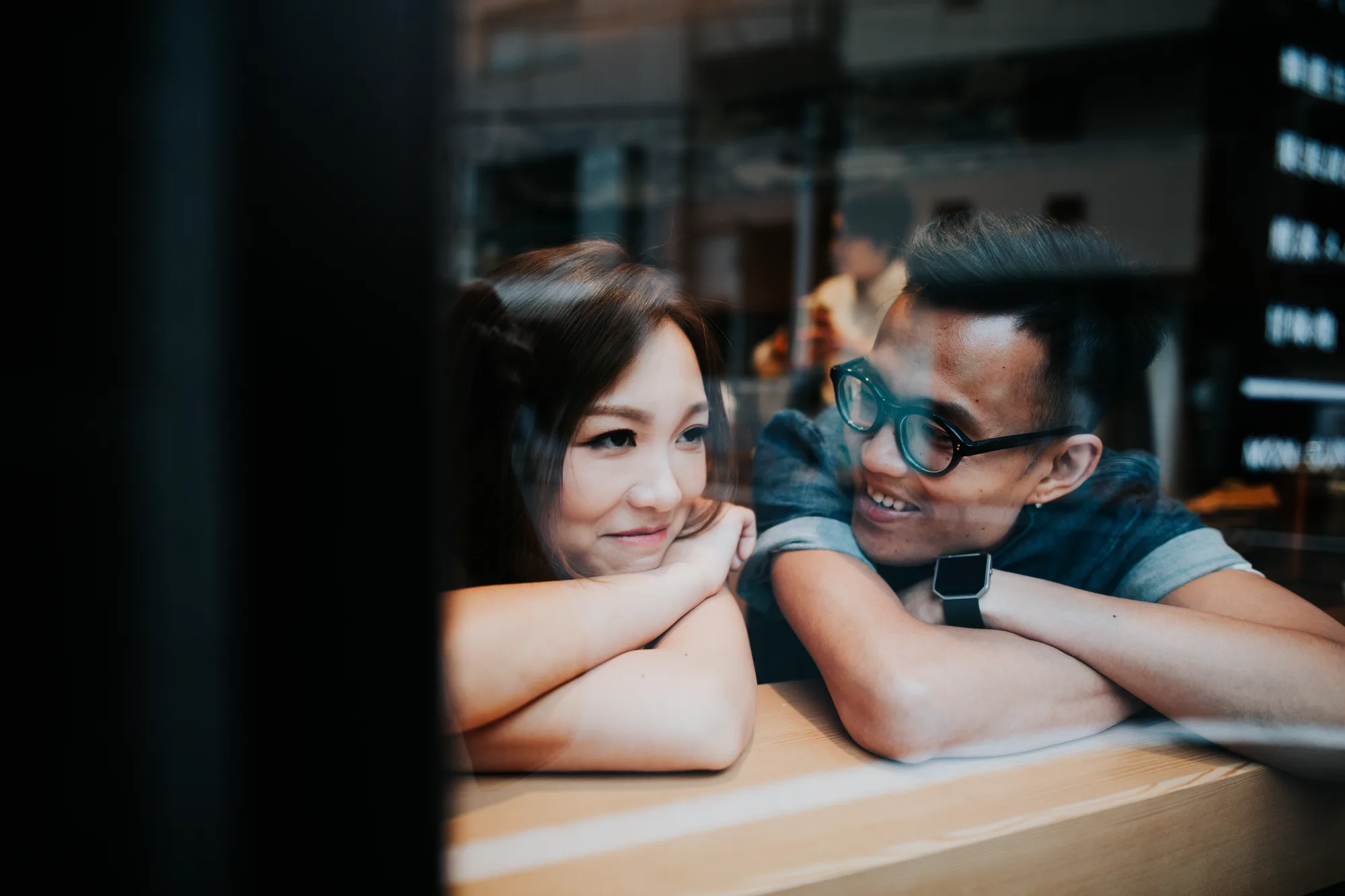 A couple shares a tender moment at a café window